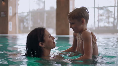 caucasian-woman-and-her-little-son-are-having-fun-in-swimming-pool-preschooler-boy-is-teaching-to-swim